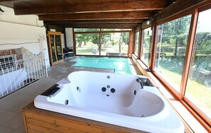 A spa area with a hot tub, wooden deck, and large windows overlooking a garden. - Maiano Relais (Sessa Aurunca)