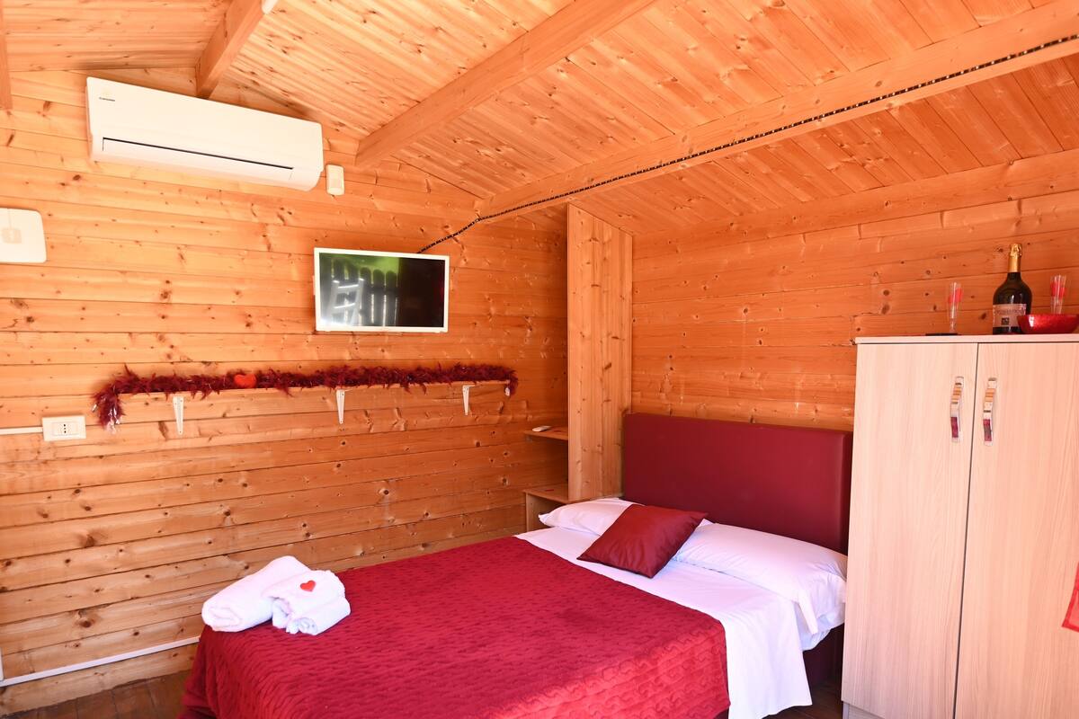 Une chambre dans un chalet en bois, équipée d’un lit, d’une télévision et d’une armoire.