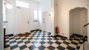 Un pasillo con piso de tablones, puertas blancas y un extintor.