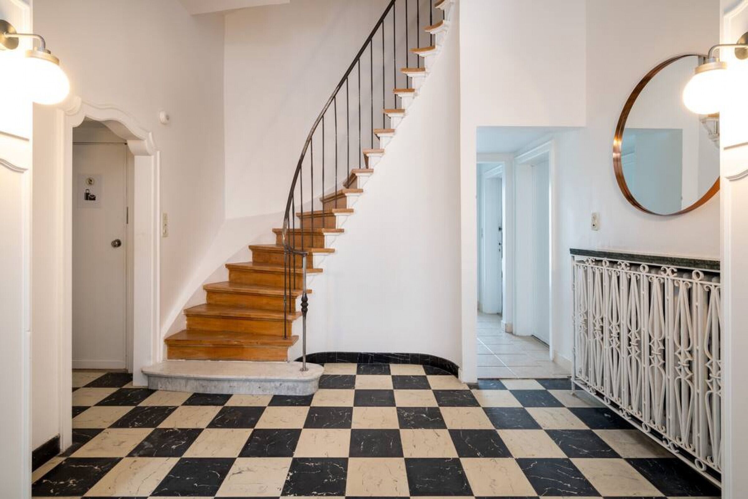 A staircase with wooden steps and a black and white checkered floor.