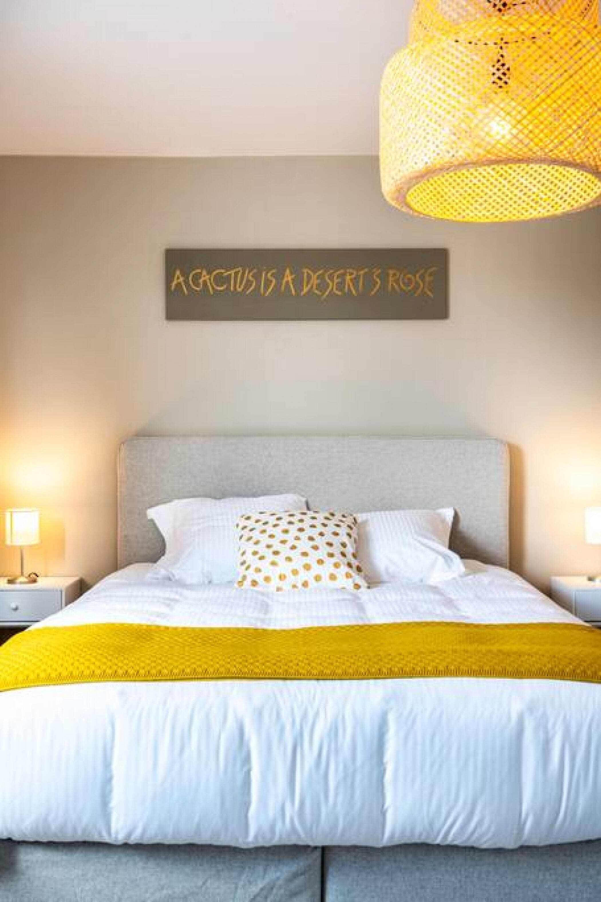 Un dormitorio con cama, un cartel en la pared y una lámpara colgante.