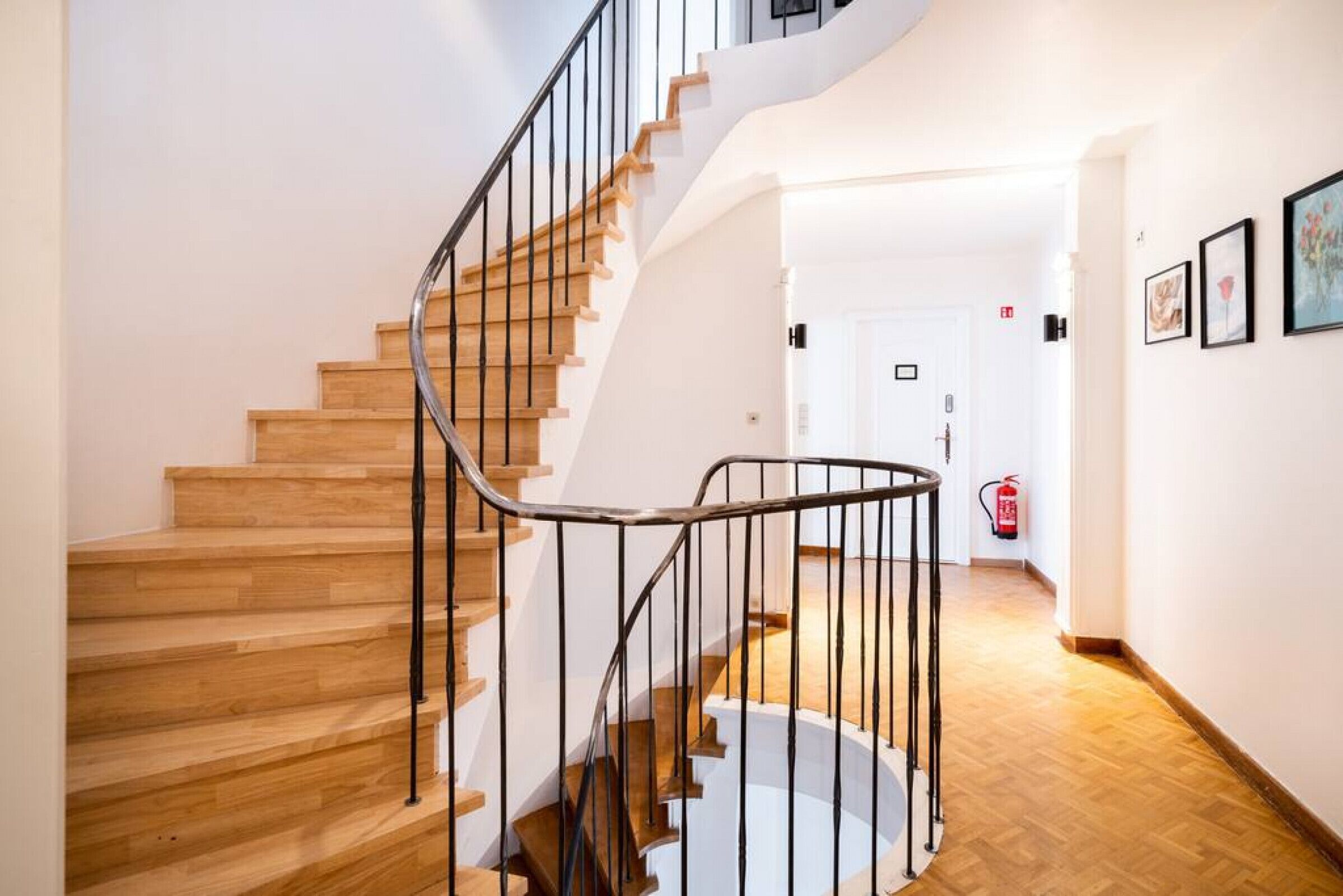 A wooden staircase with a metal railing leading to a landing.
