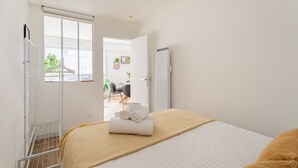 A bedroom with a bed, a window, a radiator, and a door leading to a bathroom. - Le Winston - Bel appartement proche de la plage (Dinard)