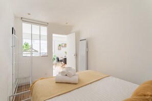 Ein Schlafzimmer mit Bett, Fenster, Heizkörper und einer Tür zu einem Badezimmer.