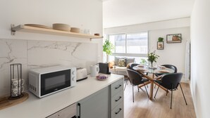 A modern kitchen with a microwave, toaster, and wooden shelves. - Le Winston - Bel appartement proche de la plage (Dinard)