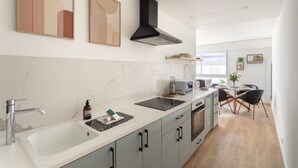 A modern kitchen with a large island, a built-in oven, and a black range hood. - Le Winston - Bel appartement proche de la plage (Dinard)