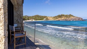 A wooden deck with chairs overlooking a beach and ocean.