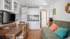 Um espaço compacto com área de refeições, cozinha compacta e sofá com almofadas.
