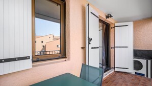 Varanda com mesa e cadeiras, porta de correr e vista para edifícios.