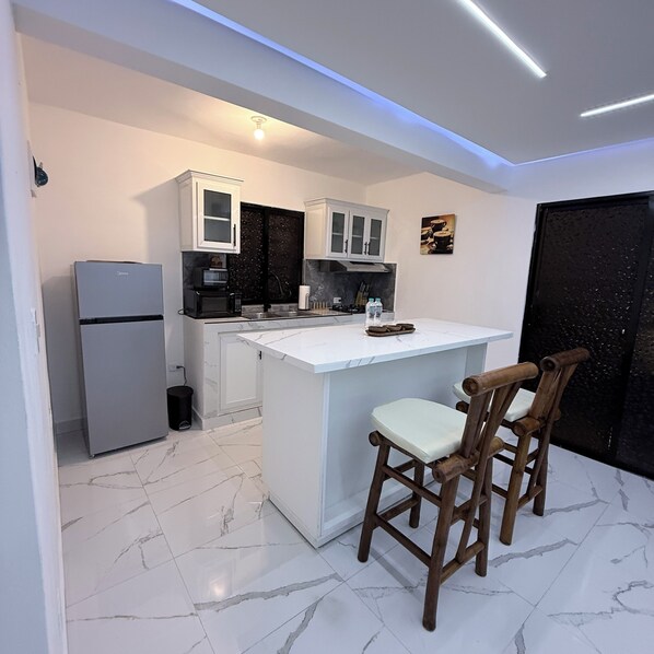 A modern kitchen with white cabinets, a built-in island, and a refrigerator.