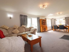 A living room with a sofa, coffee table, and dining area with chairs and a cabinet.
