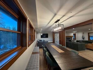 Un comedor moderno con una mesa larga, sillas y vistas amplias a través de grandes ventanales.