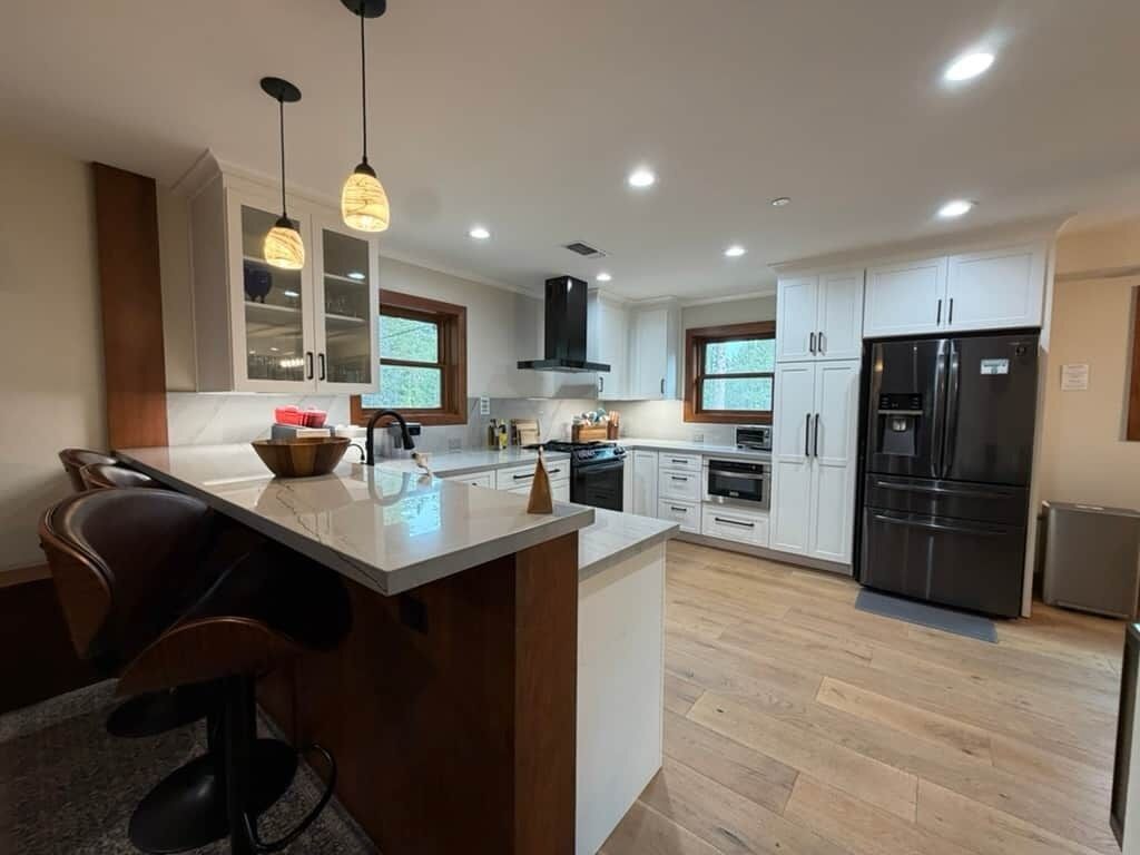 Una cocina moderna con una isla central, electrodomésticos integrados e iluminación colgante.