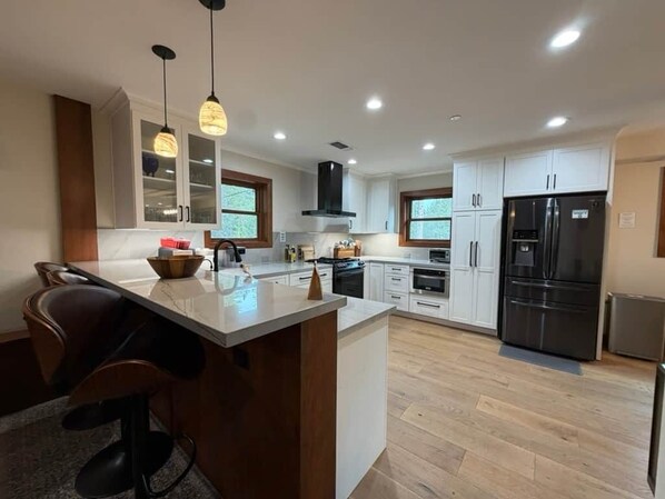 A modern kitchen with a central island, built-in appliances, and pendant lighting.