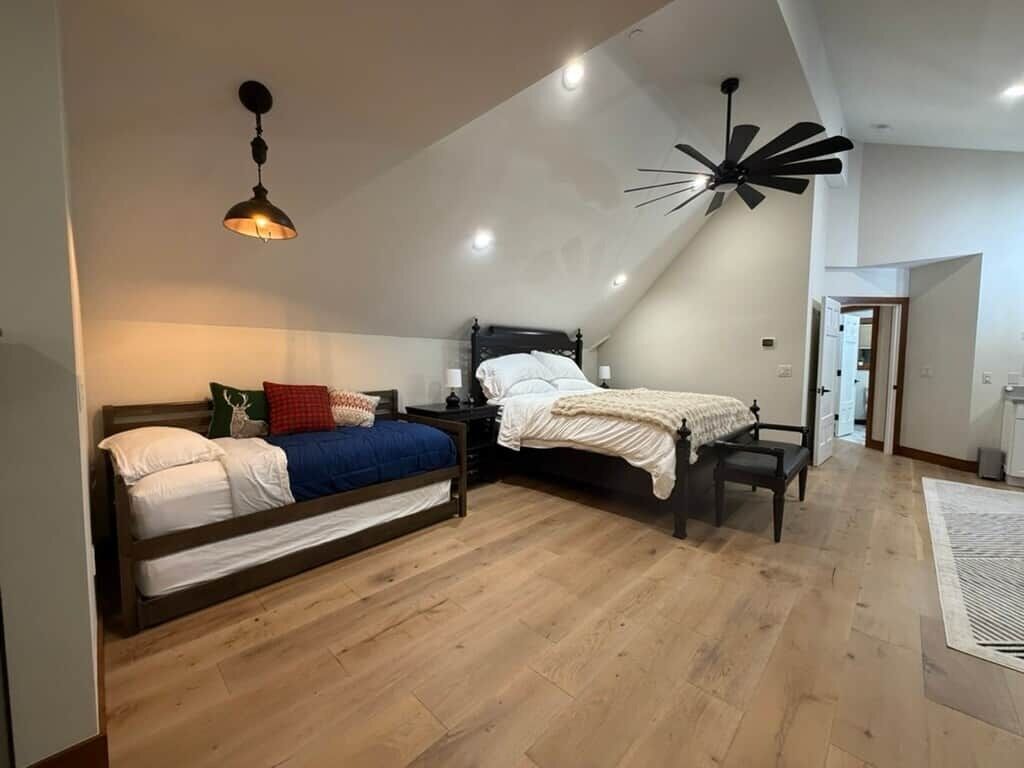 Un dormitorio con dos camas, un ventilador de techo y una lámpara moderna.