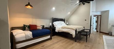 Un dormitorio con dos camas, un ventilador de techo y una lámpara moderna.
