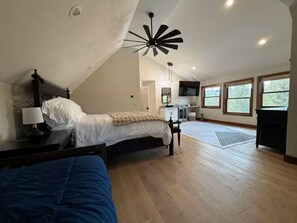 Ein Schlafzimmer mit Bett, Nachttisch, Lampe, Deckenventilator und Fenster.