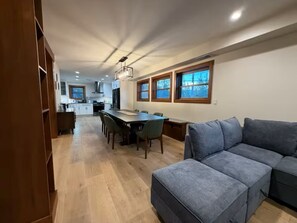 Eine moderne Küche mit Holzschränken, einem Esstisch mit Stühlen und einem grauen Sofa.