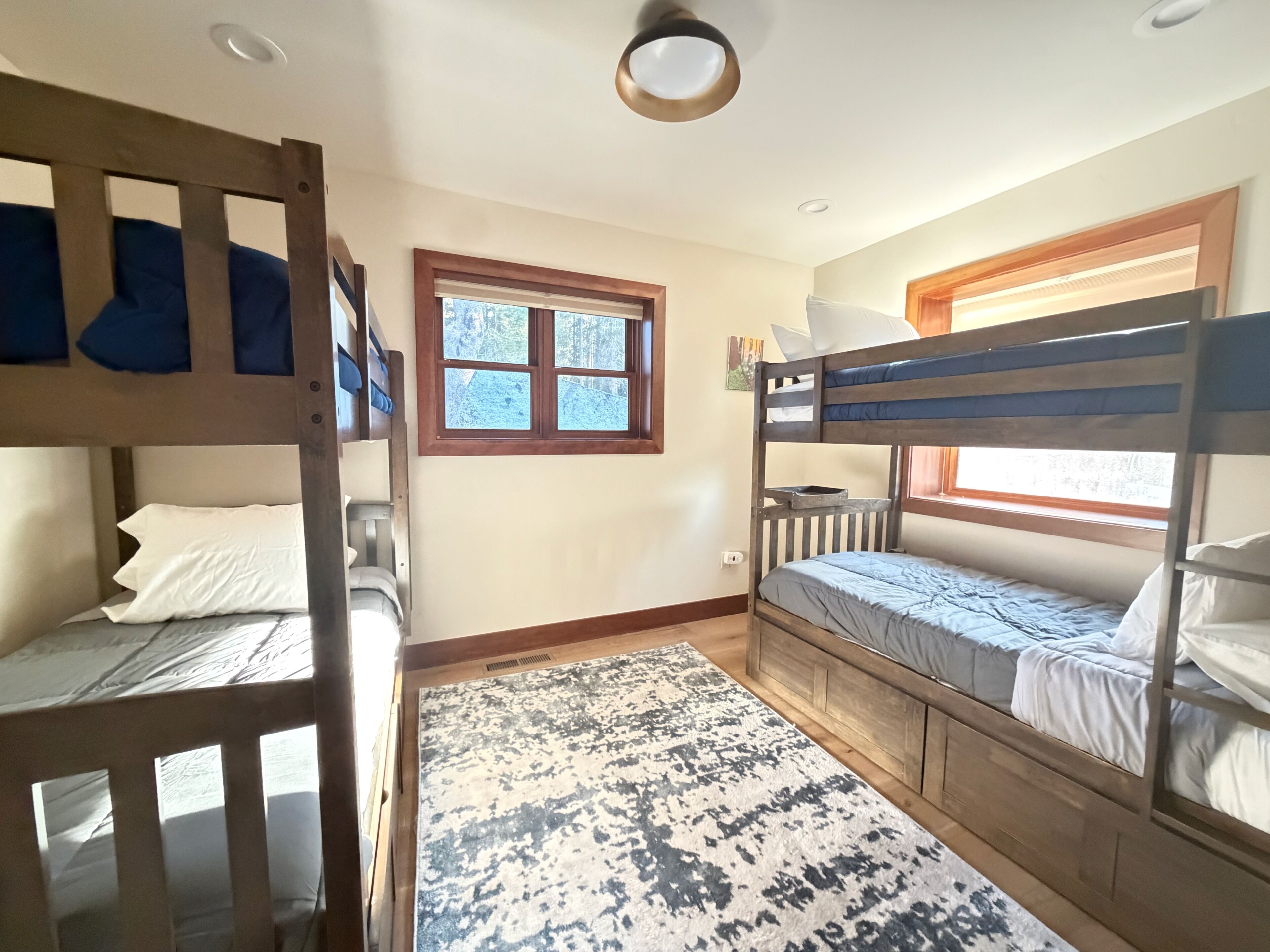 Ein Zimmer mit Etagenbetten, einem Fenster und einem gemusterten Teppich.