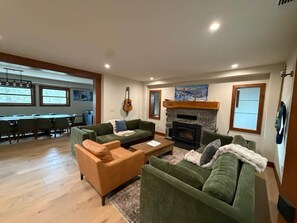 A living room with a fireplace, green sofas, a coffee table, and a guitar. - Historic Stone Villa - Minutes to Sugar Bowl with Sauna and EV Charger (Soda Springs)