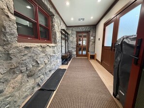 A hallway with stone walls, a wooden door, and a black mat leading to a room. - Historic Stone Villa | Donner | Sauna | EV Charger (Soda Springs)