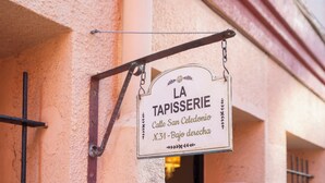 Skilt for 'LA TAPISSERIE' med en metalbeslag, fastgjort til en bygning.