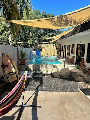 A pool area with a hammock, lounge chairs, and a surfboard. - Blue Horizon Room 2 A California style open studio with direct pool view (Taminique)