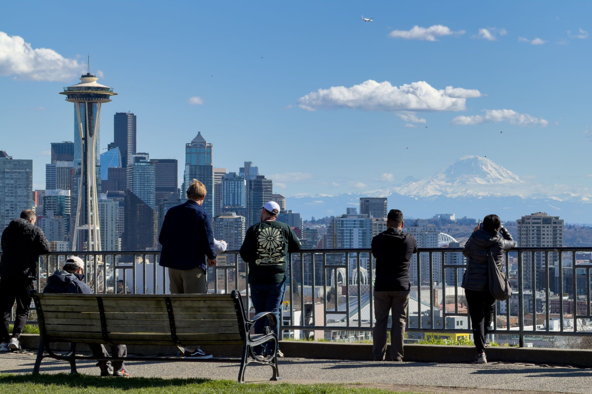 A cityscape with a prominent tower, a snow-capped mountain, and a bridge in the background.