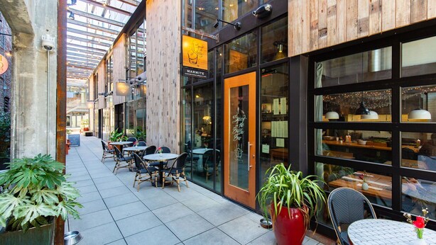 Un espace extérieur abrité avec des tables et des chaises, une vitrine et un mur intérieur en bois.