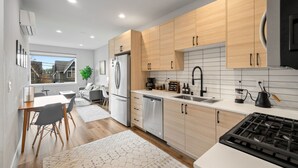 Une cuisine moderne avec des meubles en bois, des appareils en acier inoxydable et un plan de travail blanc.