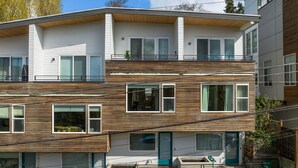 Un immeuble résidentiel moderne à plusieurs étages, doté d’un balcon, de grandes fenêtres et d’une adresse bien visible.