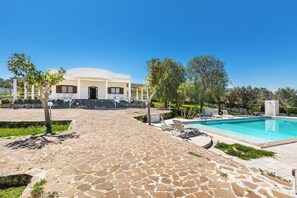 A pool area with a stone pathway leading to a building with a white facade and a pool. - Villa Carlotta by Perle di Puglia (Ostuni)