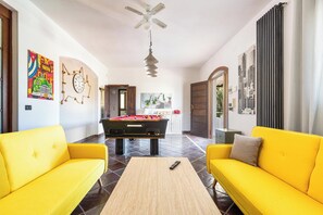 A bright living room with yellow sofas, a pool table, and a ceiling fan. - Villa Carlotta by Perle di Puglia (Ostuni)