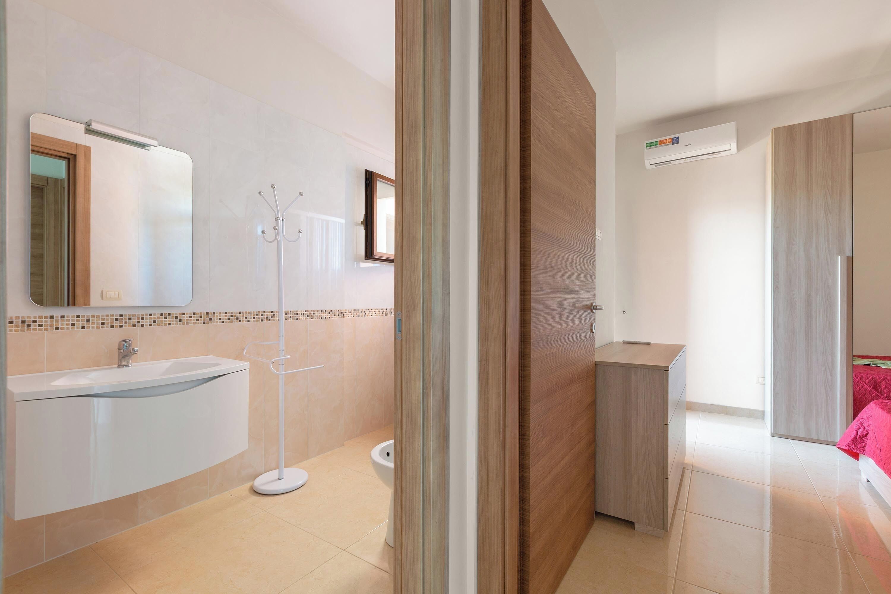 Et moderne badeværelse med vask, spejl og toilet.