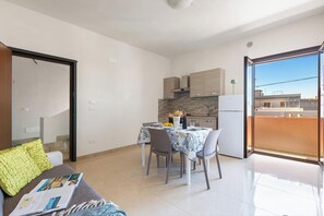 Ein kompakter Wohnraum mit Essbereich, Küchenzeile und einem Balkon mit Blick.