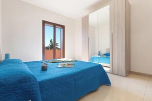 A bedroom with two beds, a large mirror, and a sliding door leading to a balcony. - Santoro Apartments - Trilo PP by BarbarHouse (Melendugno)