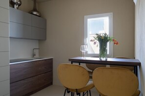 A modern kitchen with a dining table, two chairs, a vase with flowers, and a window. - Infinito Luxury Rooftop by BarbarHouse (Monopoli)