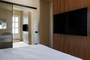 A modern hotel room with a bed, a TV mounted on the wall, and a sliding door leading to a bathroom. - Infinito Luxury Rooftop by BarbarHouse (Monopoli)
