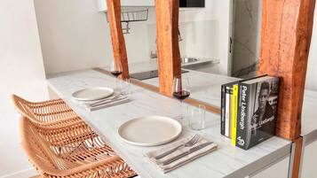 A dining area with a white marble table, two wicker chairs, and a book titled 'Peter Lindtberg'.