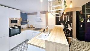 A modern kitchen with a central island, built-in appliances, and a unique ceiling design.