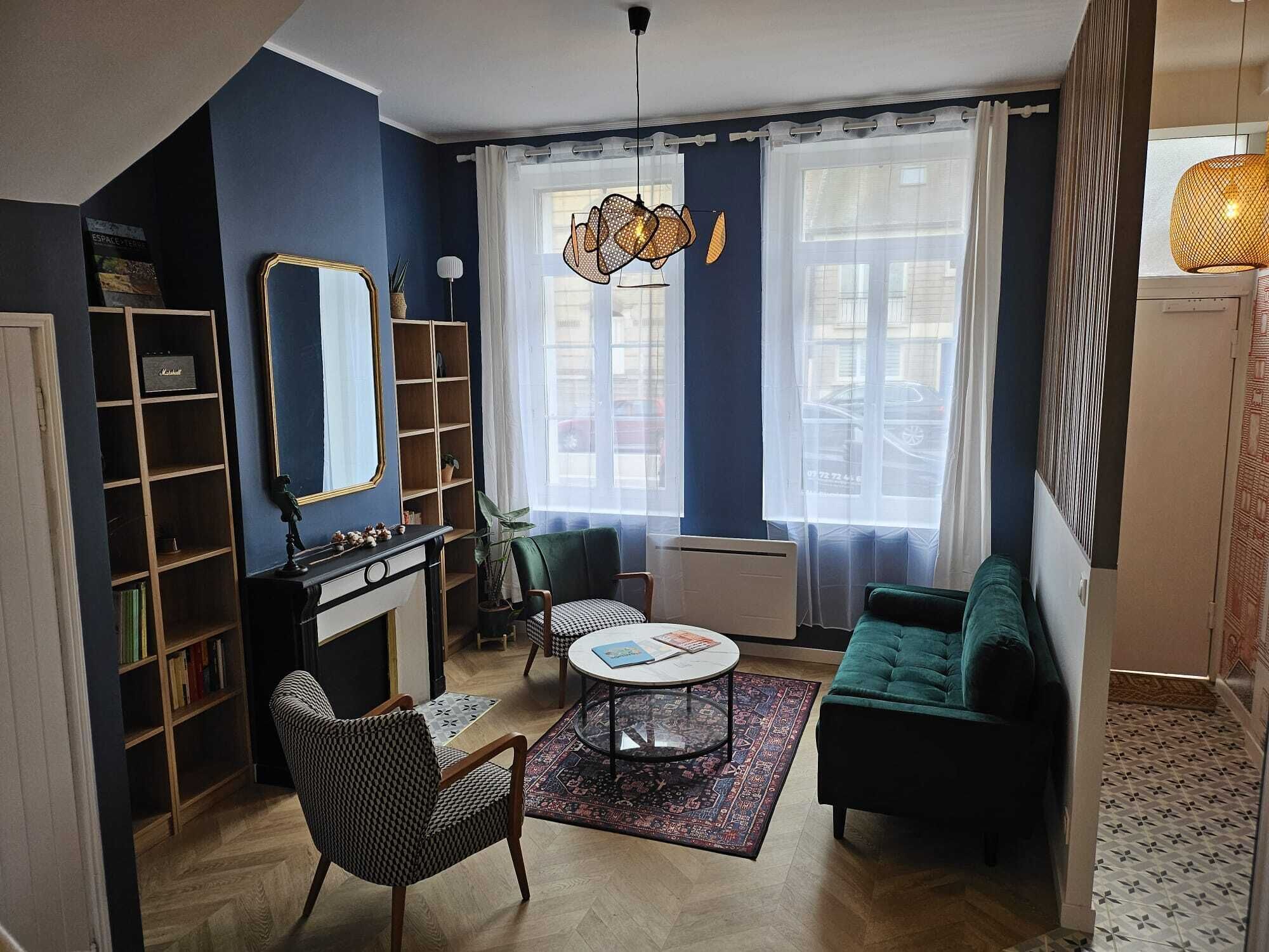 Una sala de estar con chimenea, un sofá, un sillón, una mesa de centro y una estantería.