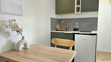 Una cucina compatta con un piccolo frigorifero, un lavandino e una sedia di legno.
