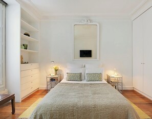 A bedroom with a large bed, two bedside tables, a wardrobe, and a mirror on the wall. - Marais 2B with Balcony by Melvane Luxury (Paris)