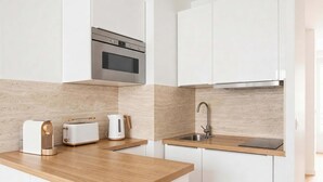 Een moderne keuken met een magnetron, broodrooster en waterkoker op het aanrecht, een spoelbak en een houten werkblad.
