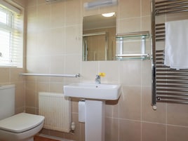 A bathroom with a white toilet, a sink, a mirror, and a towel rack.