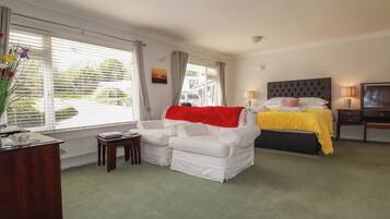 A hotel room with a bed, a sofa, a desk, and a window with blinds.