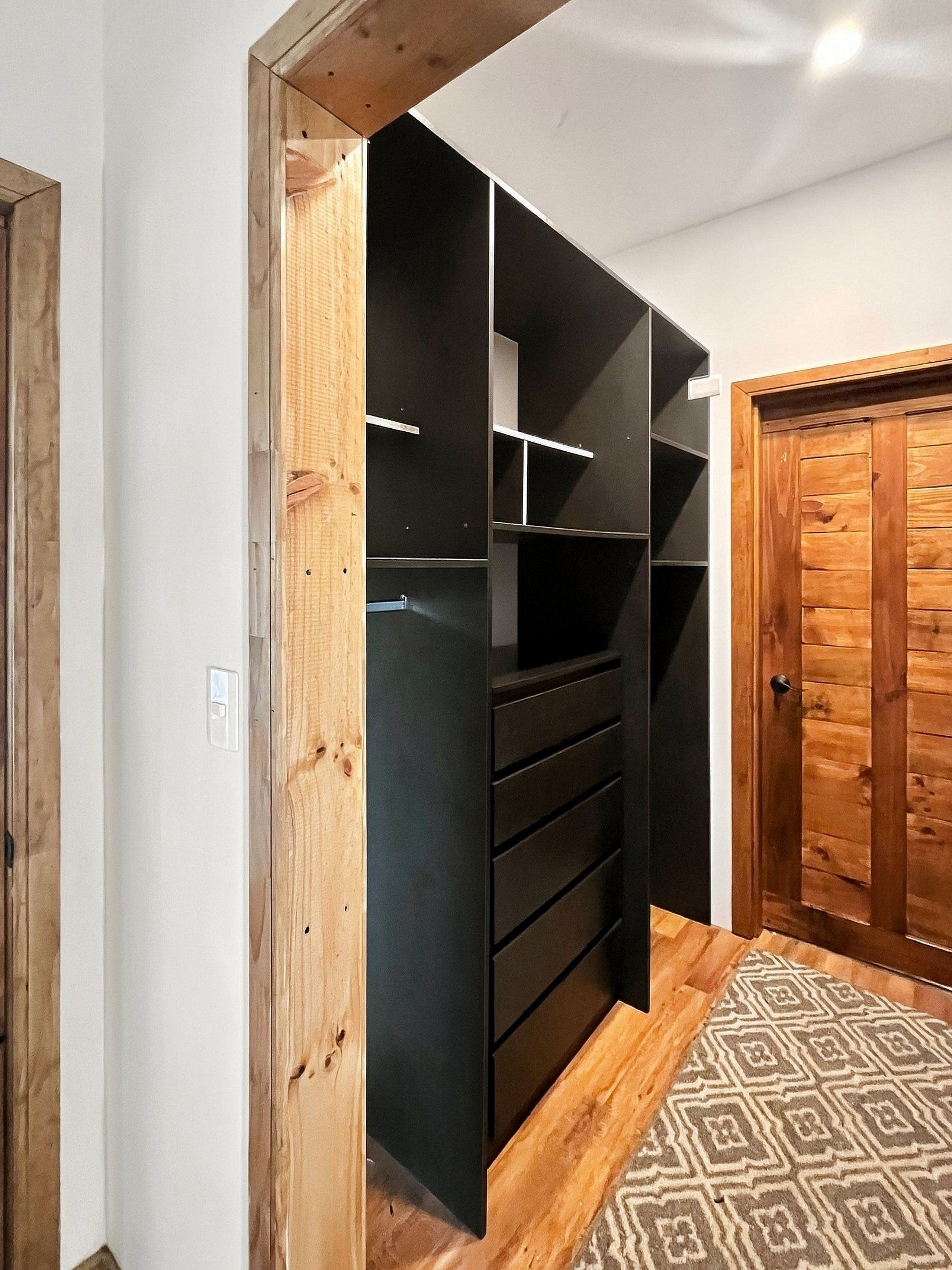 Une pièce dotée d’une armoire intégrée, d’une porte en bois et d’un tapis à motifs.