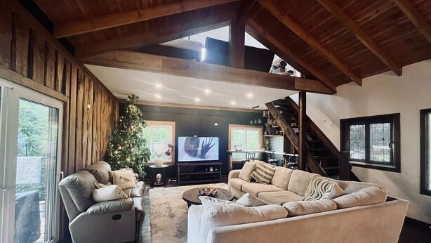 Un amplio salón con un gran ventanal, un árbol de Navidad, una chimenea y una escalera.