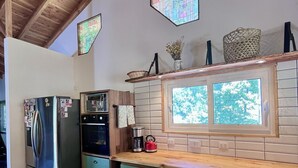 Una cocina con techo de madera, refrigerador, horno, ventana con vista y armarios verdes.
