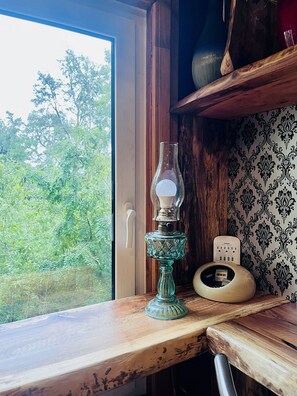 A room with a wooden table, a glass lamp, a wall socket, and a window with a view of greenery. - Oceana Suites Lago Panguipulli (Panguipulli)